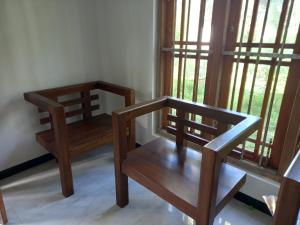Duas cadeiras de madeira num quarto com janelas em Chamara home stay em Ratgama Hegoda