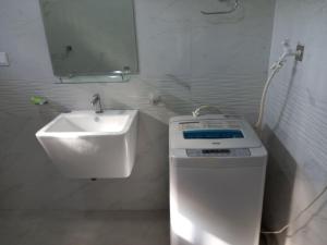 y baño blanco con lavabo y lavadora. en Chamara home stay, en Ratgama Hegoda