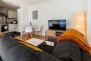 a living room with a couch and a television at Central Gem: Cosy 2BR with Private Balcony in Manchester