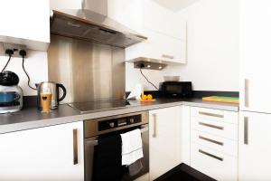 a kitchen with white cabinets and stainless steel appliances at Central Gem: Cosy 2BR with Private Balcony in Manchester