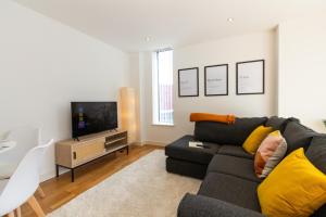 a living room with a couch and a tv at Central Gem: Cosy 2BR with Private Balcony in Manchester