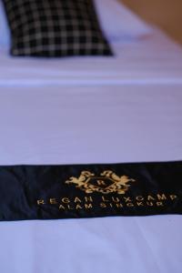 a pillow on a bed with a black and white blanket at Regan Luxcamp by Digihub Hospitality in Palayangan