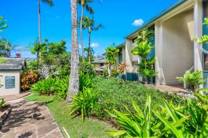 ein Haus mit Palmen und Pflanzen in der Unterkunft Gardens at West Maui in Lahaina