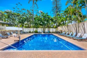 a swimming pool with chaise lounge chairs and trees at Gardens at West Maui in Lahaina