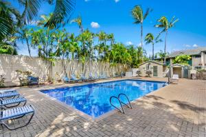 a swimming pool with chairs and palm trees at Gardens at West Maui in Lahaina