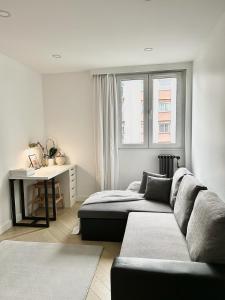 ein Wohnzimmer mit einem Sofa und einem Schreibtisch in der Unterkunft GRAND Appartement F3 Proche de Gare RER B in Le Bourget