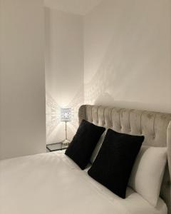 um quarto com uma cama com almofadas pretas e brancas em Cardiff/Penarth Home em Cardiff
