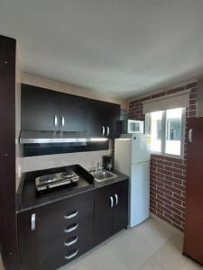 een keuken met een wastafel en een witte koelkast bij R.1102 Lindo estudio ejecutivo en área turística. in Panama-Stad