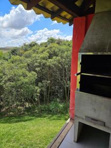 an outdoor oven with a view of a field at Chalés Vila Real - Tranquilidade na Serra de Carrancas - Piscina com uma vista espetacular do Pôr do Sol in Carrancas