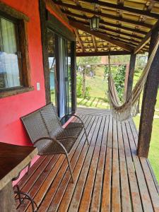 a porch with two chairs and a hammock on a house at Chalés Vila Real - Tranquilidade na Serra de Carrancas - Piscina com uma vista espetacular do Pôr do Sol in Carrancas