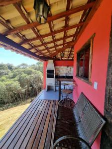 a deck with a bench and a grill on a house at Chalés Vila Real - Tranquilidade na Serra de Carrancas - Piscina com uma vista espetacular do Pôr do Sol in Carrancas