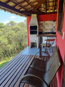 a porch with a bench and a stove at Chalés Vila Real - Tranquilidade na Serra de Carrancas - Piscina com uma vista espetacular do Pôr do Sol in Carrancas