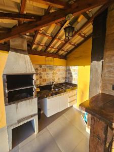 a large kitchen with a stove and a sink at Chalés Vila Real - Tranquilidade na Serra de Carrancas - Piscina com uma vista espetacular do Pôr do Sol in Carrancas