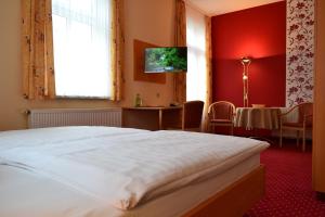 a bedroom with a bed and a table and a window at Hotel-Pension Vier Jahreszeiten in Bad Elster