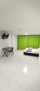 a room with a bed and a table and a green curtain at HOTEL PROVENZA MEDELLIN in Medellín
