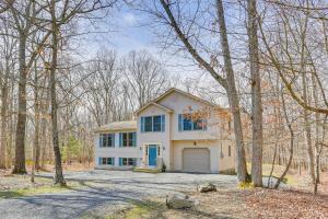 una casa blanca con un garaje en el bosque en Forest-View Deck and Fire Pit Poconos Escape!, en East Stroudsburg