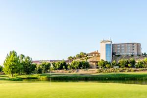 ein Golfgrün mit einem Gebäude im Hintergrund in der Unterkunft Hotel Doña Brígida – Salamanca Forum in Villamayor
