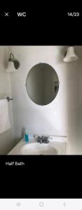 a bathroom with a sink and a round mirror at LOVELY RENOVATED 2 BEDROOM HOME WITH FREE Parking in Albany