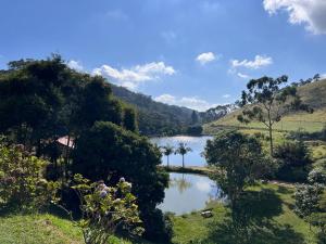 a lake in the middle of a field with trees at Hotel Fazenda Upã Moña in Vassouras