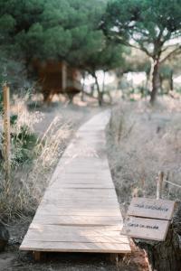 a wooden path in a field with a sign at miCielo - Baumhäuser in Vejer de la Frontera