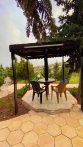 um pátio com uma mesa e cadeiras debaixo de um guarda-sol em مزارع وشاليهات للايجار في جرش em Gérasa