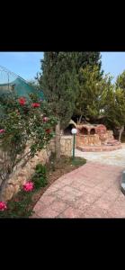 um jardim com flores cor-de-rosa e uma parede de pedra em مزارع وشاليهات للايجار في جرش em Gérasa