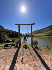 un columpio frente a un lago con un barco en Hotel Fazenda Upã Moña en Vassouras