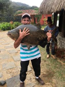 Un uomo che tiene un pesce grosso tra le mani di Hotel Fazenda Upã Moña a Vassouras