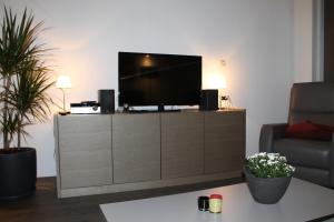 a living room with a flat screen tv on a cabinet at Huisje Zeertevree in Nieuwvliet