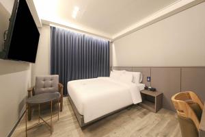 a hotel room with a white bed and a television at H Avenue Hotel Geumho in Gwangju