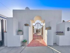 a white building with a gate and potted plants at Casa Georgia at Kino Bay - Moderna y acogedora. in Bahía Kino