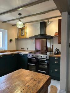 kuchnia z czarnymi urządzeniami i drewnianym stołem w obiekcie The Old Forge w mieście Cheltenham