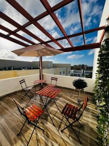 eine Terrasse mit Stühlen, Tischen und einem Sonnenschirm auf dem Dach in der Unterkunft La rose in Punta Cana