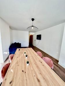 uma grande mesa de madeira num quarto com cadeiras cor-de-rosa em Superbe appartement Paris/Bagnolet 203 em Bagnolet