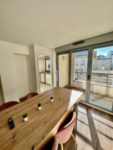 a wooden table in a room with a large window at Superbe appartement Paris/Bagnolet 203 in Bagnolet