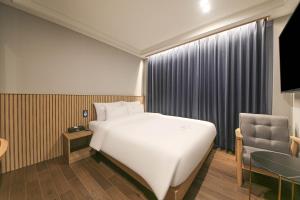 a bedroom with a bed and a chair and a table at H Avenue Hotel Geumho in Gwangju