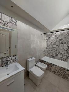 een badkamer met een toilet, een wastafel en een bad bij Hermosa y amplia casa nueva in Puerto Madryn