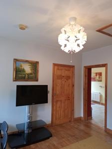 sala de estar con TV de pantalla plana y lámpara de araña en Welcome to Tunmobi Villa, its home away from home., en Ballyjamesduff