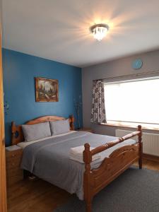 - une chambre avec un lit aux murs bleus et une fenêtre dans l'établissement Welcome to Tunmobi Villa, its home away from home., à Ballyjamesduff