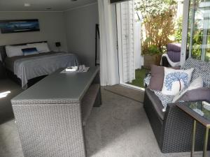 a bedroom with a bed and a table and a couch at Tranquil Garden Studio in Tauranga