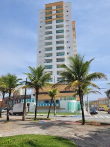 um edifício alto com palmeiras em frente em Condomínio Firenze em Mongaguá