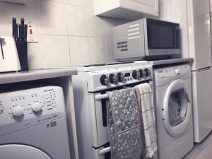 a kitchen with a washing machine and a microwave at Stunning 2 Bedroom Flat Next to Victoria Hospital in Fife