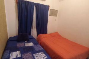 a bedroom with a bed and a window with blue curtains at Casa para 8 personas in Zihuatanejo +15 photos