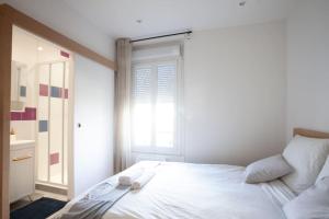 Schlafzimmer mit einem Bett mit weißer Bettwäsche und einem Fenster in der Unterkunft 2 pièces Cosy - proche RER A - proche Paris in Houilles