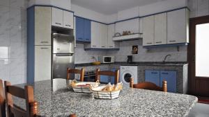 a kitchen with blue cabinets and a counter with chairs at Casa Fenteira in Poio +17 photos