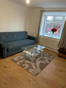 a living room with a blue couch and a glass table at Charming Escape: 2BR Home with Parking in Aveley