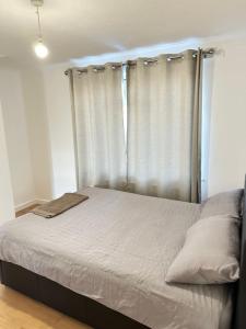 a bed in a bedroom with a curtain at Charming Escape: 2BR Home with Parking in Aveley