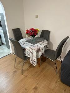 a table with chairs and a vase of flowers on it at Charming Escape: 2BR Home with Parking in Aveley +19 photos