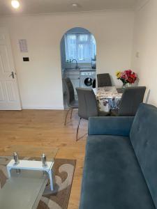 a living room with a blue couch and a table at Charming Escape: 2BR Home with Parking in Aveley