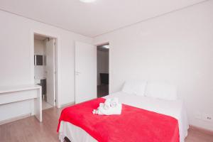 Habitación blanca con cama con manta roja en Apartamento Aconchegante Maia 404, en Caxias do Sul